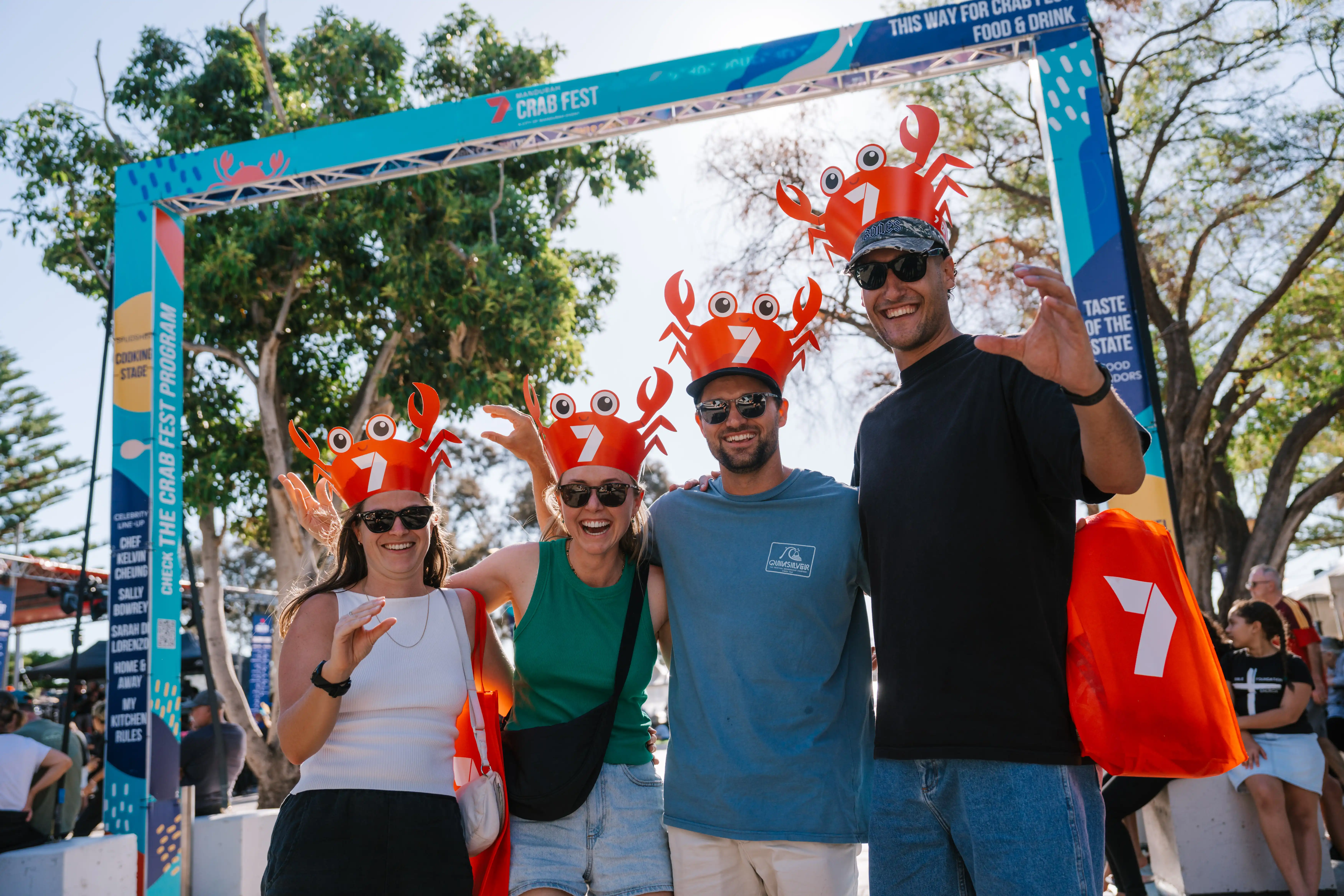Four people smiling and wearing red Crab Fest hats